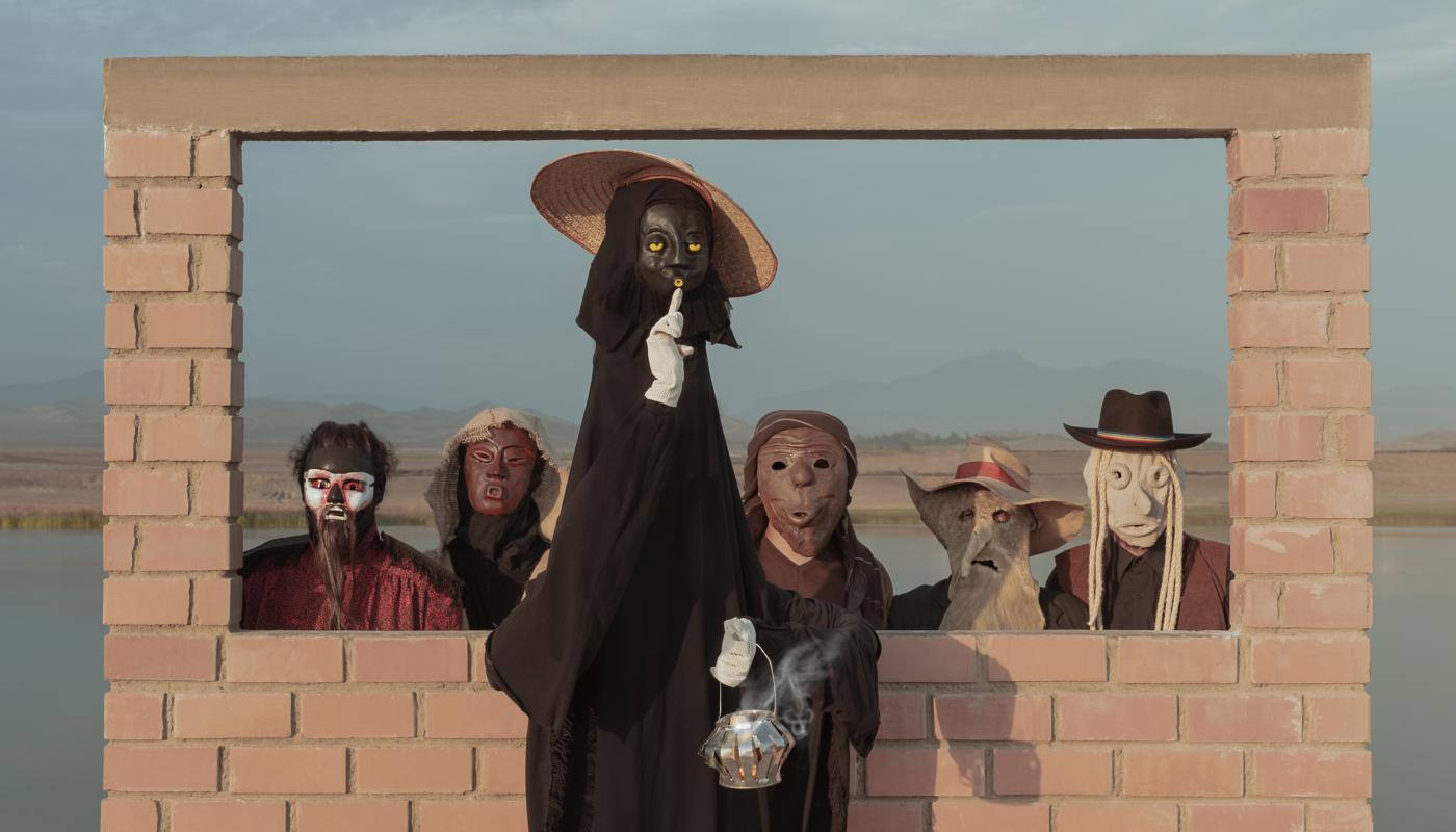 5 people wearing masks in front of a brick structure