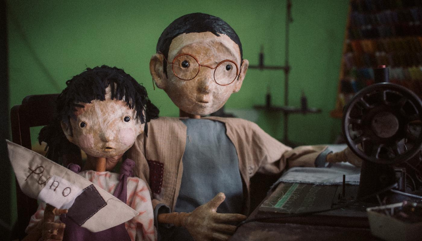 Puno, Sewing Memories, photo by Rangga Yudhistir Two puppets looking at the camera, one with a sewing machine and one with a small boat