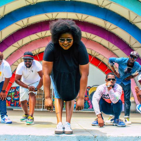 BCUC by Shudo Lubengo A woman stands in front of four other men, posing in front of a large rainbow like structure