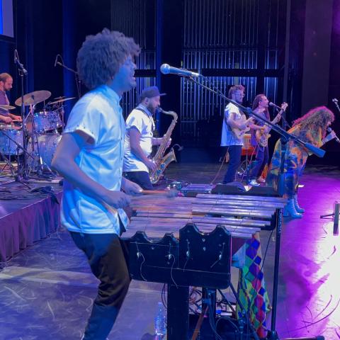 Image of a band performing on stage featuring a man playing the marimba.